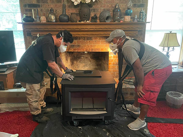wood burning fireplace installation technicians wearing masks install fireplace